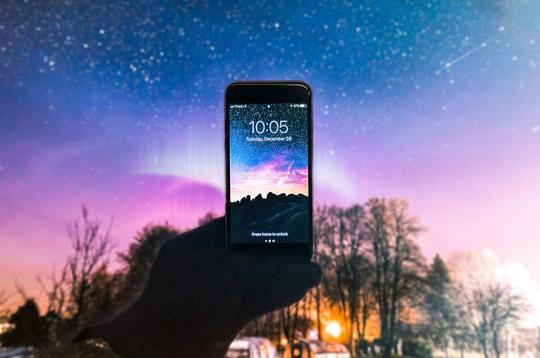 Mobiltelefon holdt opp mot farget himmel